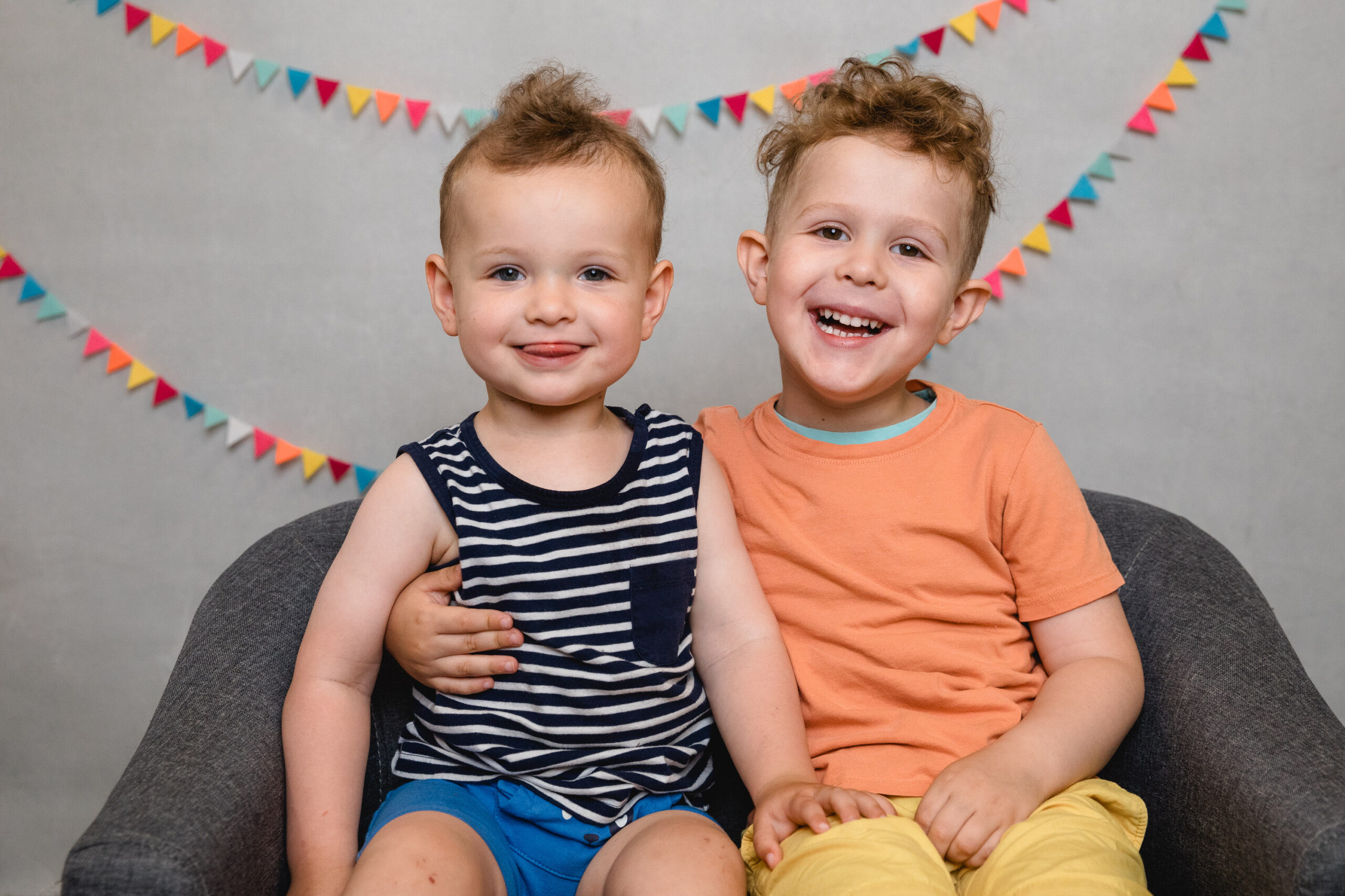 Zwei lachende Kindergartenkinder vor einer bunten Wimpelkette