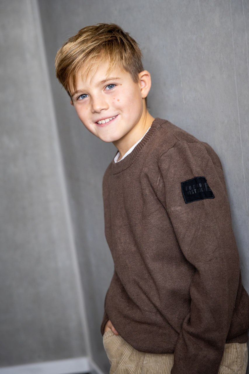 Junge im braunen Pullover vor grauem Hintergrund