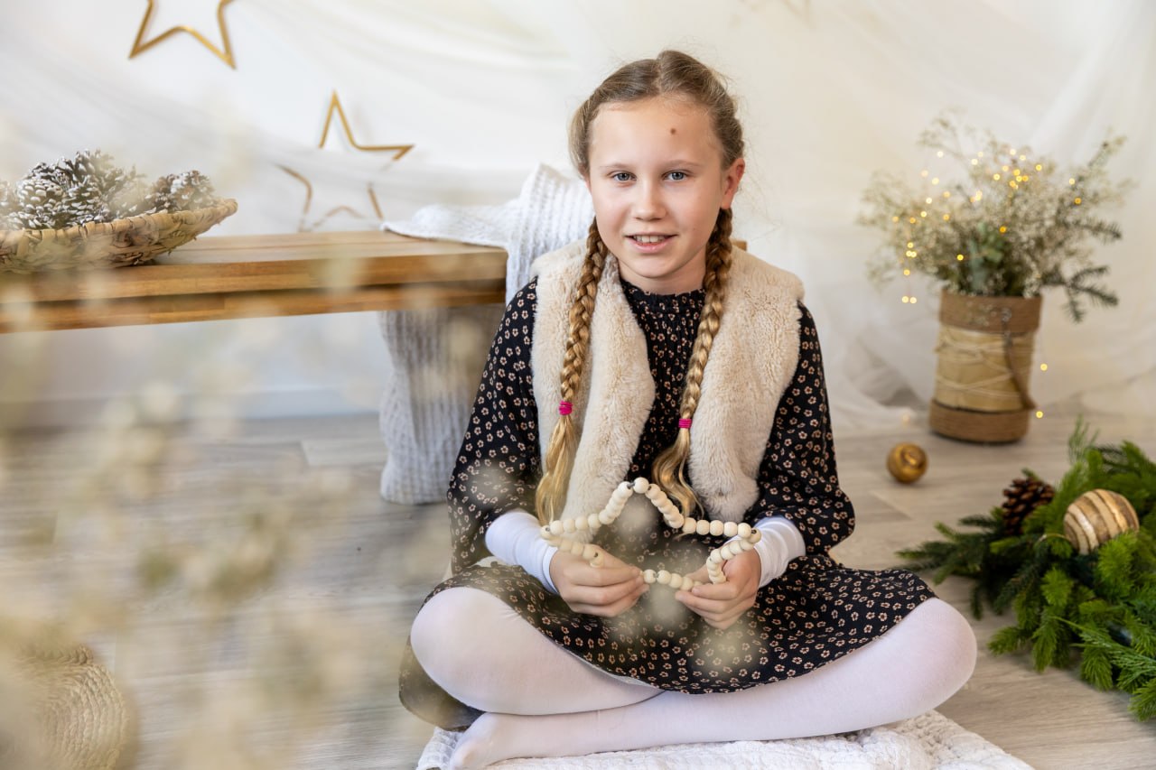 Mädchen im hellen Weihnachtsset mit Tannenzweigen