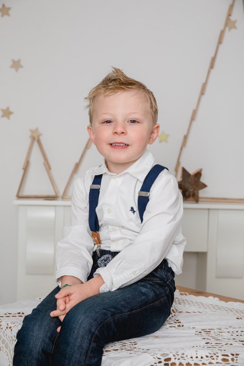 Kleiner Junge im weißen Weihnachtsset mit Schneeflocken