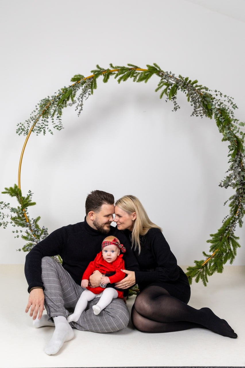Familie mit Baby unter einem weihnachtlichen Tannenkranz